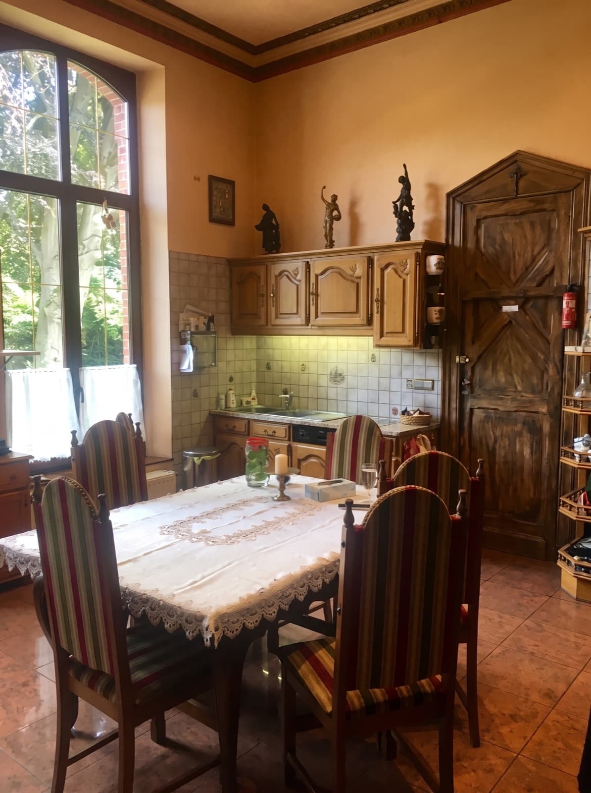 Coin repas du château d'Hourpes sous un plafond de plus de trois mètres, châssis cintré et sol en terre cuite
